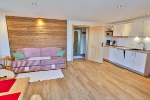 A modern kitchen with white cabinets and a wooden accent wall. - Holiday apartment with 1 bedroom (Schliersee)