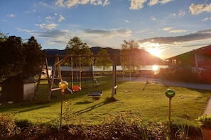 A playground with swings and a slide, a grassy area, and a building in the background. - Holiday apartment with 1 bedroom (Schliersee)
