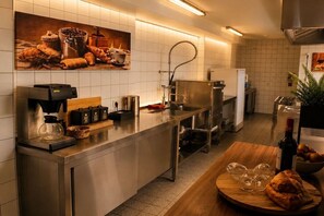 A modern kitchen with stainless steel appliances, a coffee machine, and a wooden table with bread and wine glasses. - Your dream villa | Villa Olsberg (Olsberg-Wulmeringhausen)