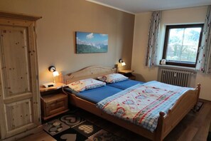 Un dormitorio con una cama de madera, dos mesitas de noche con lámparas, una ventana con cortinas y un cuadro en la pared.
