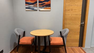Una habitación con una mesa redonda de madera y dos sillas con tapicería a cuadros.