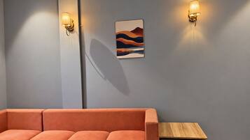 Un intérieur moderne avec un canapé d’angle, une petite table en bois et deux appliques murales.