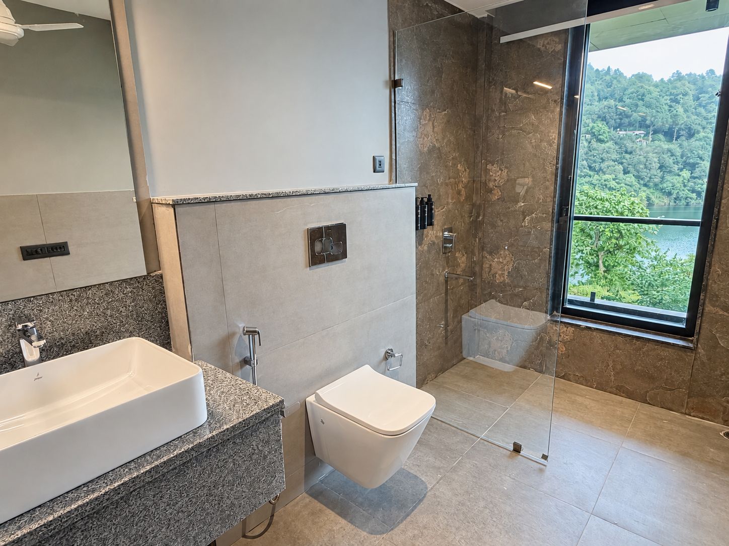 Un baño moderno con un lavamanos grande, inodoro y ducha con mampara de vidrio.