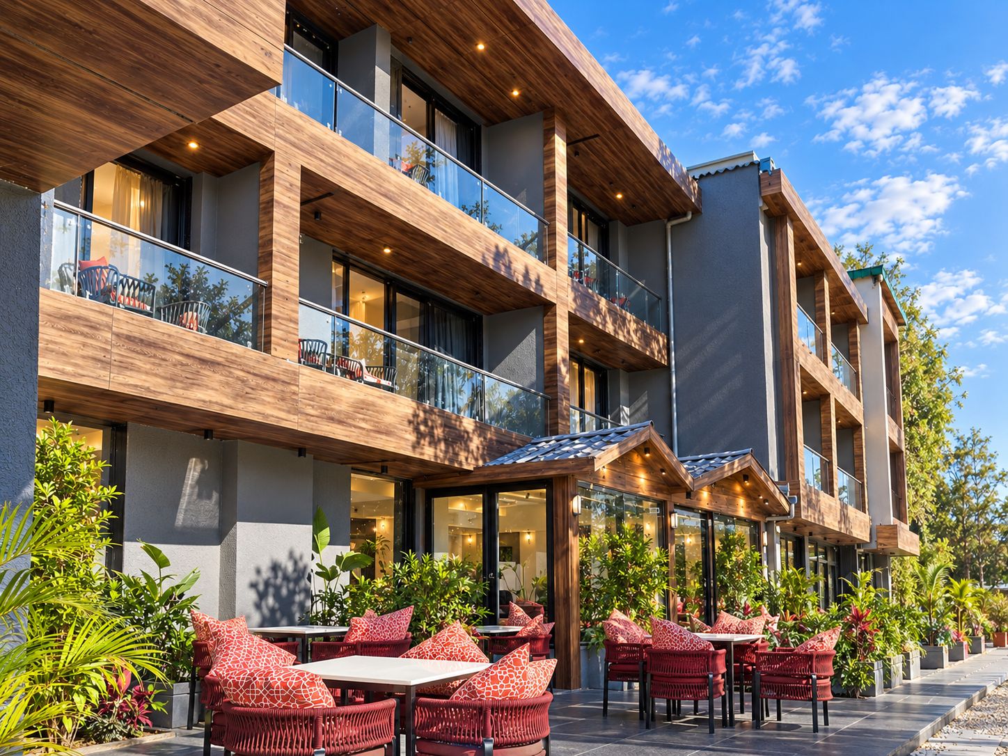Un hotel con asientos exteriores, varios balcones y un diseño arquitectónico moderno.