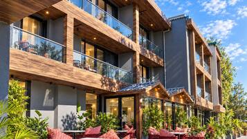Un hotel con asientos exteriores, varios balcones y un diseño arquitectónico moderno.