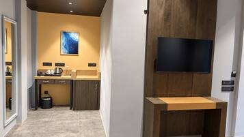 A modern kitchen with a wooden cabinet, a built-in TV, and a small wooden table.