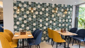 Un espace repas avec des murs ornés de motifs hexagonaux, des tables avec des chaises et des luminaires suspendus.