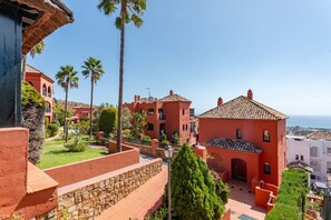 A coastal residential area with red buildings, palm trees, and a clear view of the sea. - Bonita Hills – Penthouse in Calahonda with Panoramic Sea Views & Large Terrace (Mijas)