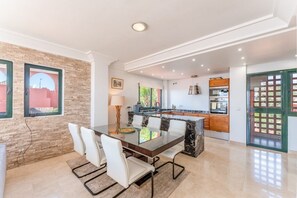 A modern kitchen with a marble island, white chairs, and a dining table. - Bonita Hills – Penthouse in Calahonda with Panoramic Sea Views & Large Terrace (Mijas)