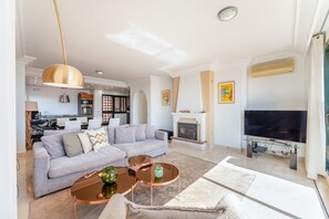 A modern living room with a sofa, coffee table, and television. - Bonita Hills – Penthouse in Calahonda with Panoramic Sea Views & Large Terrace (Mijas)