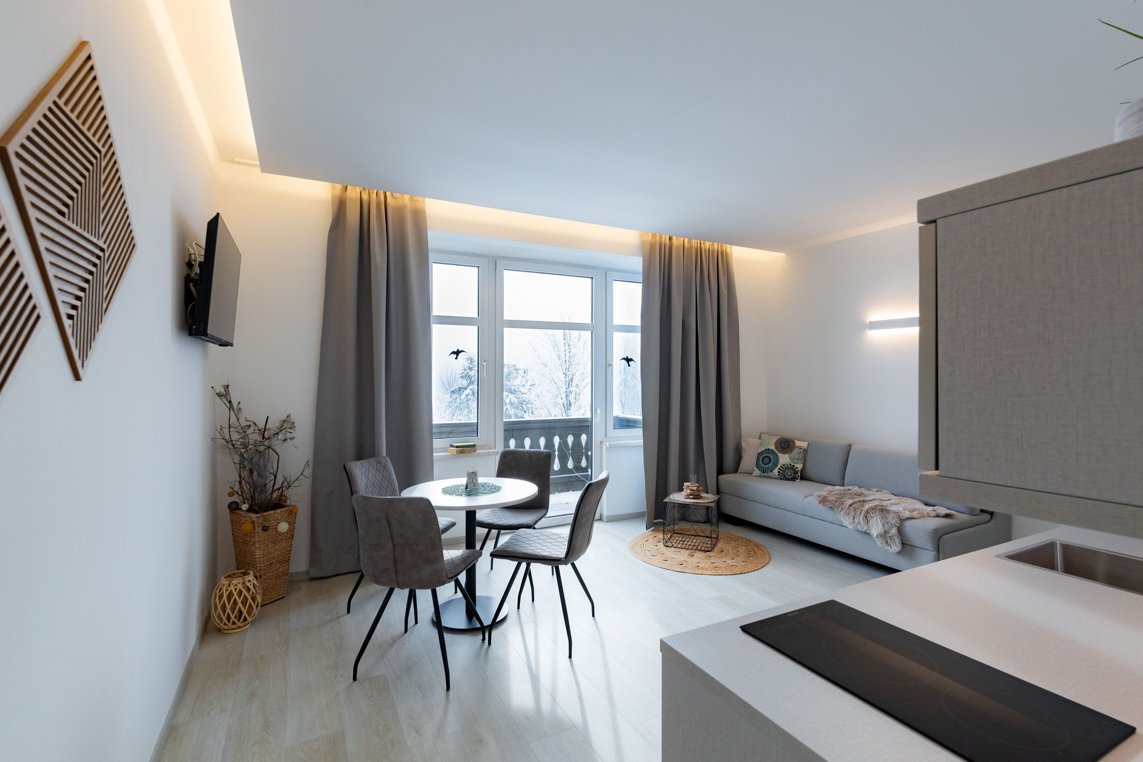 Ein modernes Wohnzimmer mit Essbereich, einer Couch und einem Fernseher.