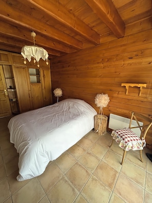 Ein Schlafzimmer einer Holzhütte mit Bett, Stuhl und Heizkörper.
