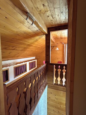 Ein Holzinnenraum mit Balkon, Holzboden und Fenster.