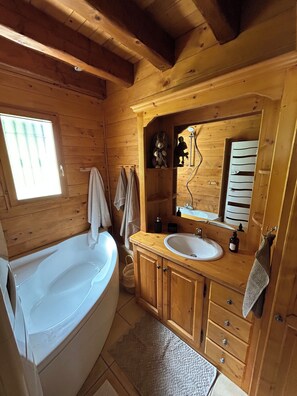 Ein Badezimmer einer Holzhütte mit Badewanne, Waschbecken und Holzschränken.