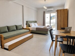 A modern hotel room with a bed, a sofa bed, a dining table with chairs, and a laptop. - 6th Floor Loft in the Heart of Athens Ι by ΜΡS (Athina)