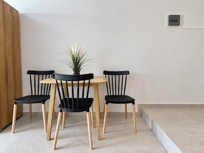 A dining area with a round table and four chairs, a potted plant on the table, and a wooden cabinet to the left. - 6th Floor Loft in the Heart of Athens Ι by ΜΡS (Athina)