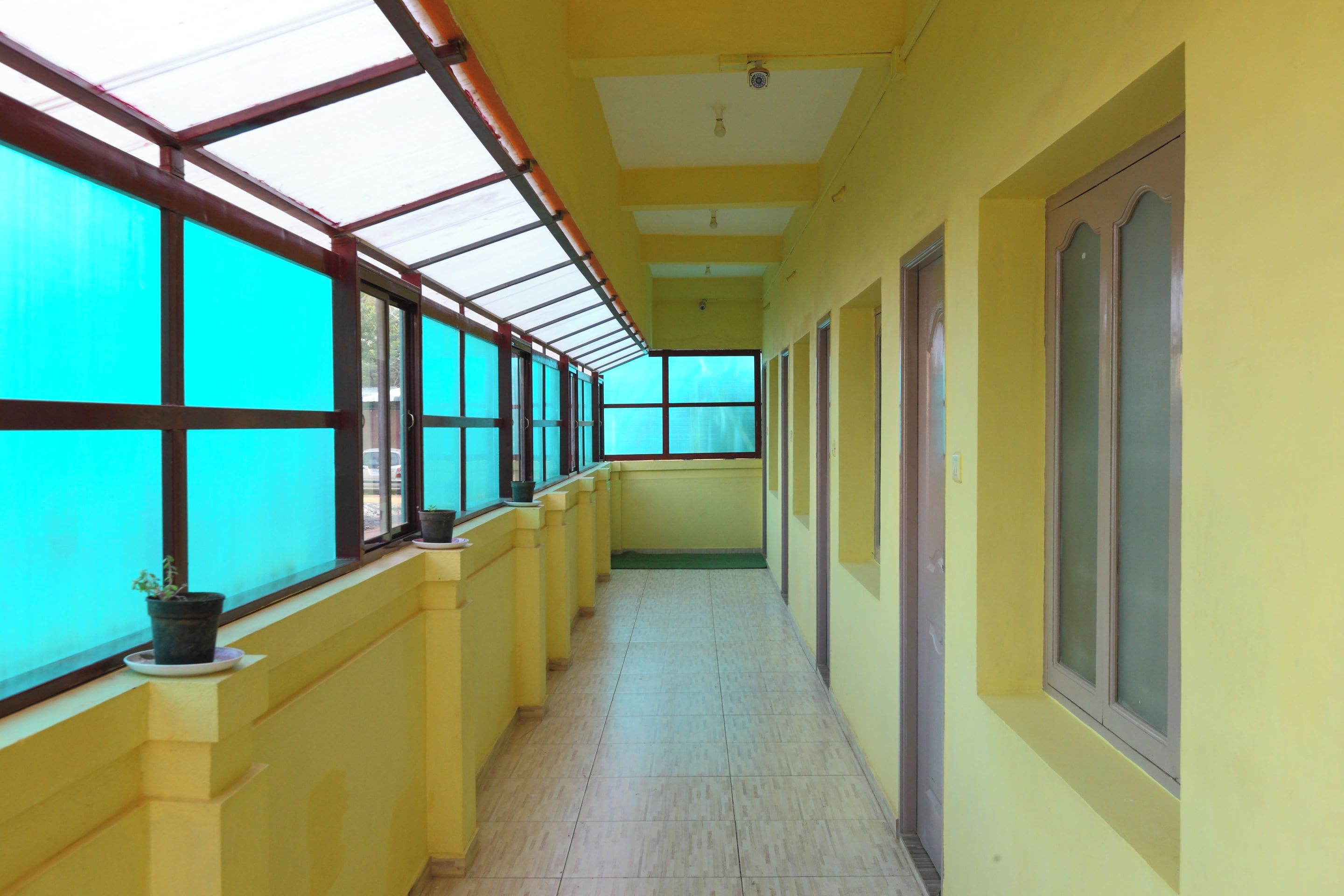 A corridor with a skylight ceiling, potted plants, and doors on one side.