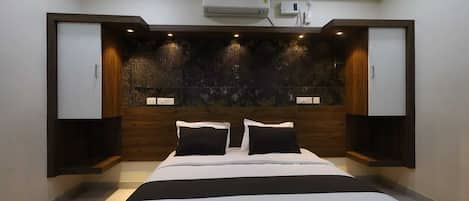 Een moderne slaapkamer met een groot bed, een vastgezet hoofdbord en een wandairconditioning.