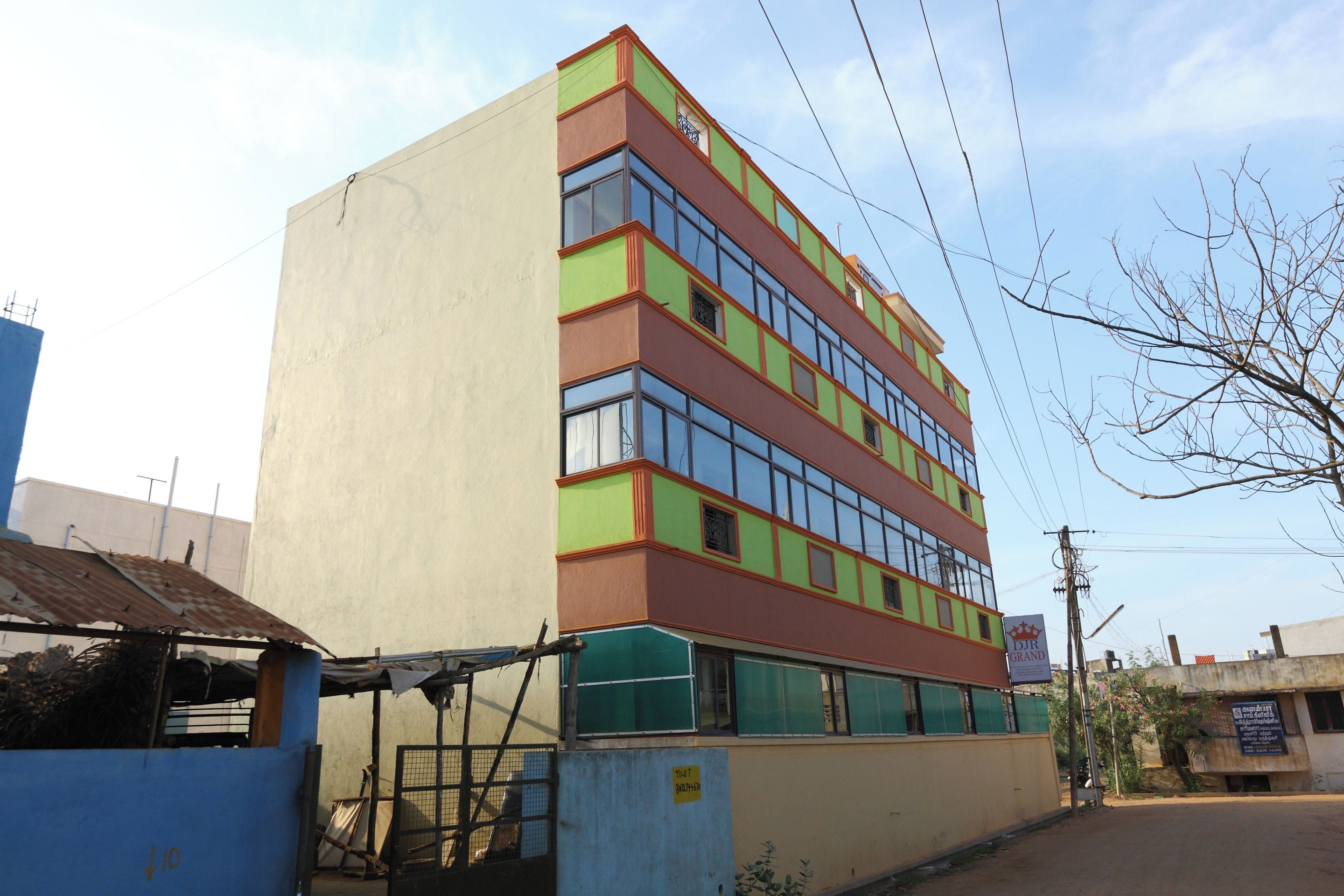 Un edificio de varios pisos con fachada plana, ventanas grandes y un letrero que indica baños.
