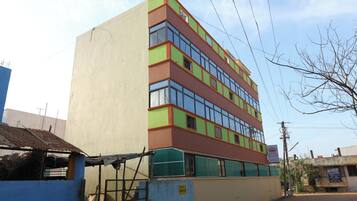 Un edificio de varios pisos con fachada plana, ventanas grandes y un letrero que indica baños.