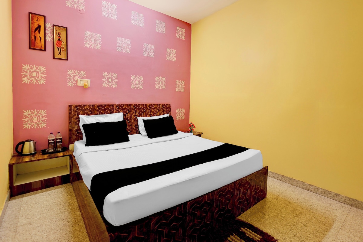 Habitació d'hotel amb llit, una tauleta de nit, un rellotge de paret i un dibuix decoratiu a la paret.