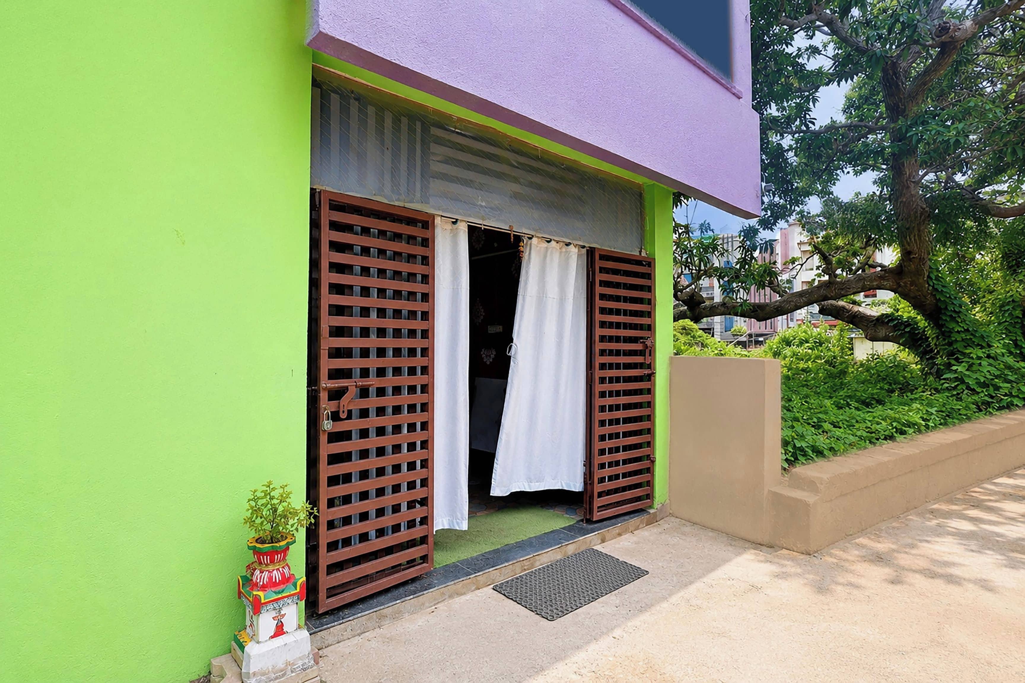 A building with a green exterior, a purple roof, and a door with brown shutters.