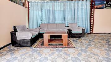 A living room with a sofa set, a coffee table, and patterned curtains.