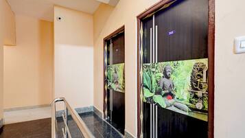 A hallway with a marble floor, a metal handrail, and doors with a Buddha statue and greenery design.