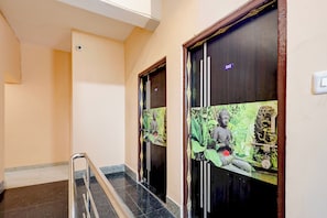 Passadís amb sòl de marbre, barana metàl·lica i portes amb motius de Budda i vegetació.