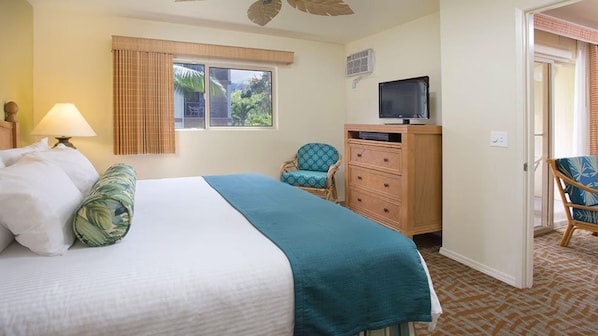 A hotel room with a bed, a chair, a dresser, and a television.