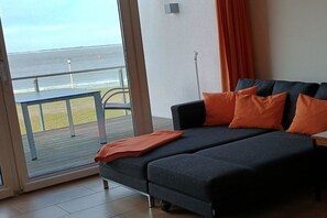 A room with a sofa bed, a view of the sea, and a balcony. - Holiday apartment Strandhaus (Norderney)