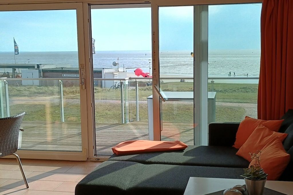 Une pièce dotée d’une grande porte-fenêtre coulissante donnant sur un balcon avec vue sur la mer.