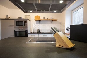 A modern kitchen with a built-in microwave, oven, and a knife block on the countertop. - Holiday home in Brilon with swimming pool (Brilon)
