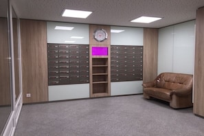 Ein Zimmer mit Aktenschrank, einer Uhr und einem Ledersofa.