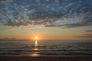 Ein Sonnenuntergang über einem Gewässer bei klarblauem Himmel.