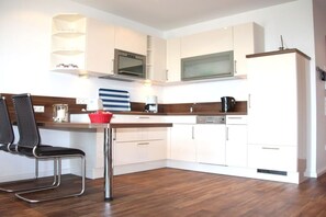 A modern kitchen with white cabinets, a stainless steel microwave, and a wooden countertop. - Holiday apartment with 2 bedrooms (Norderney)