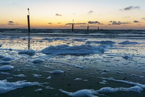 A beach with waves, a pier, and a sunset. - House Hahnen - Upper Floor (Norderney)