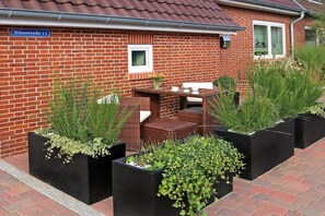 Een stenen huis met een tuin, inclusief tuinmeubilair en plantenbakken.