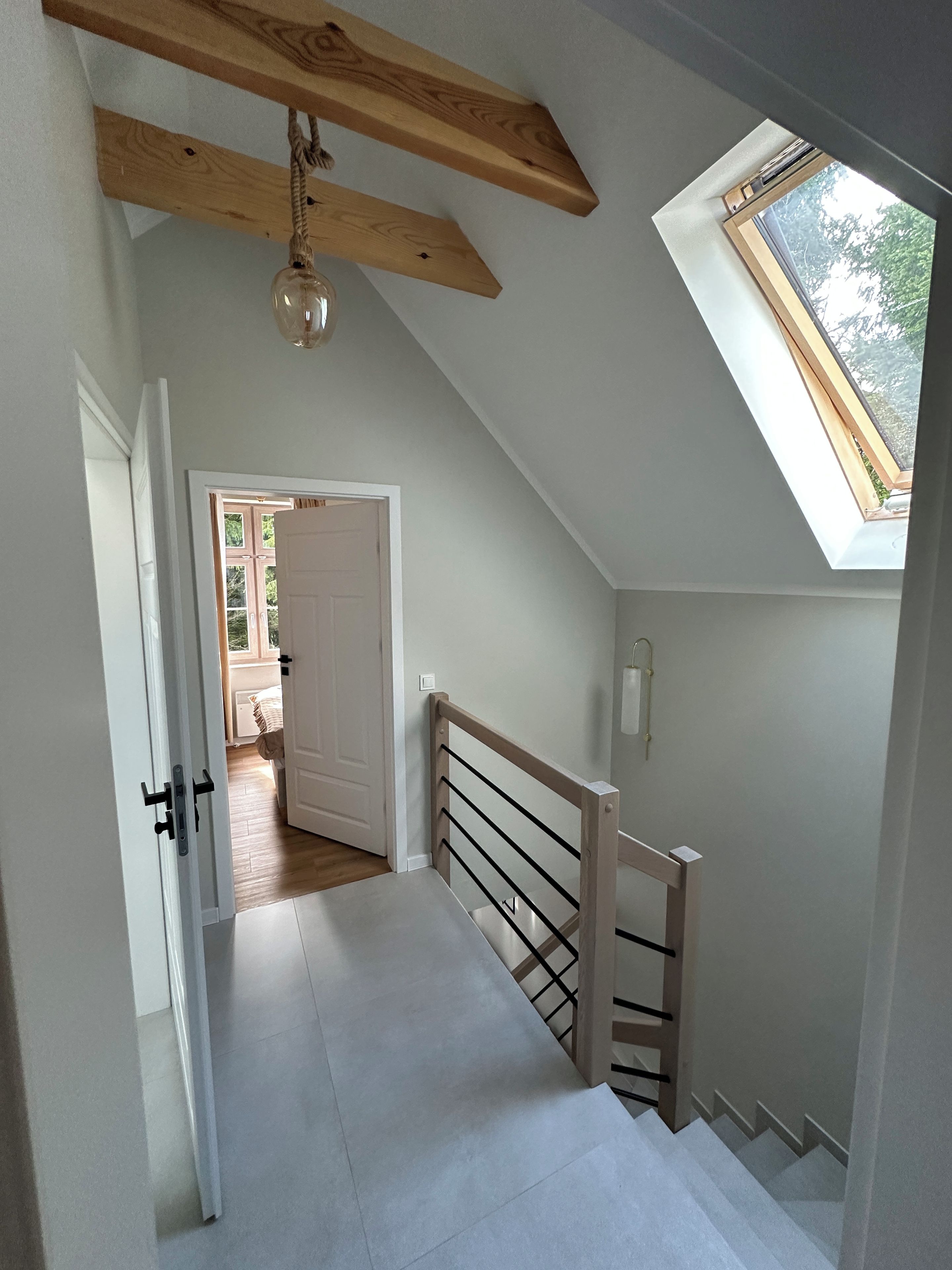 Un escalier avec une rampe en bois et une lucarne.