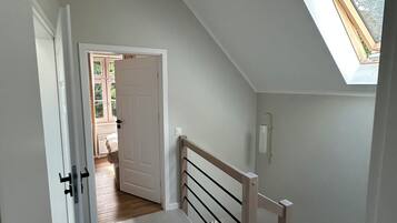 A staircase with a wooden handrail and a skylight.