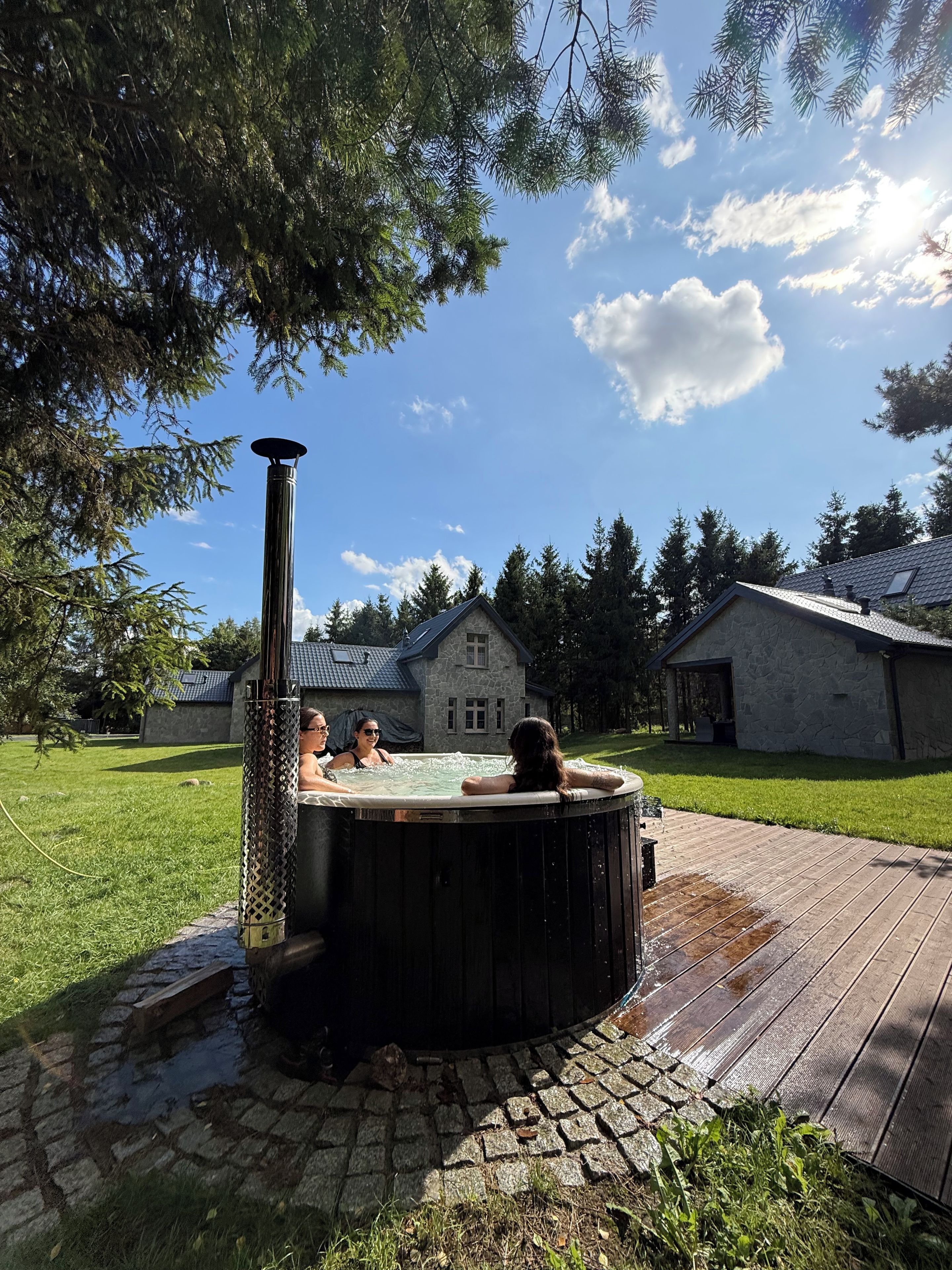 Un bain à remous dans un jardin, avec une maison en pierre en arrière-plan.
