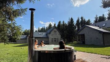 Un bain à remous dans un jardin, avec une maison en pierre en arrière-plan.