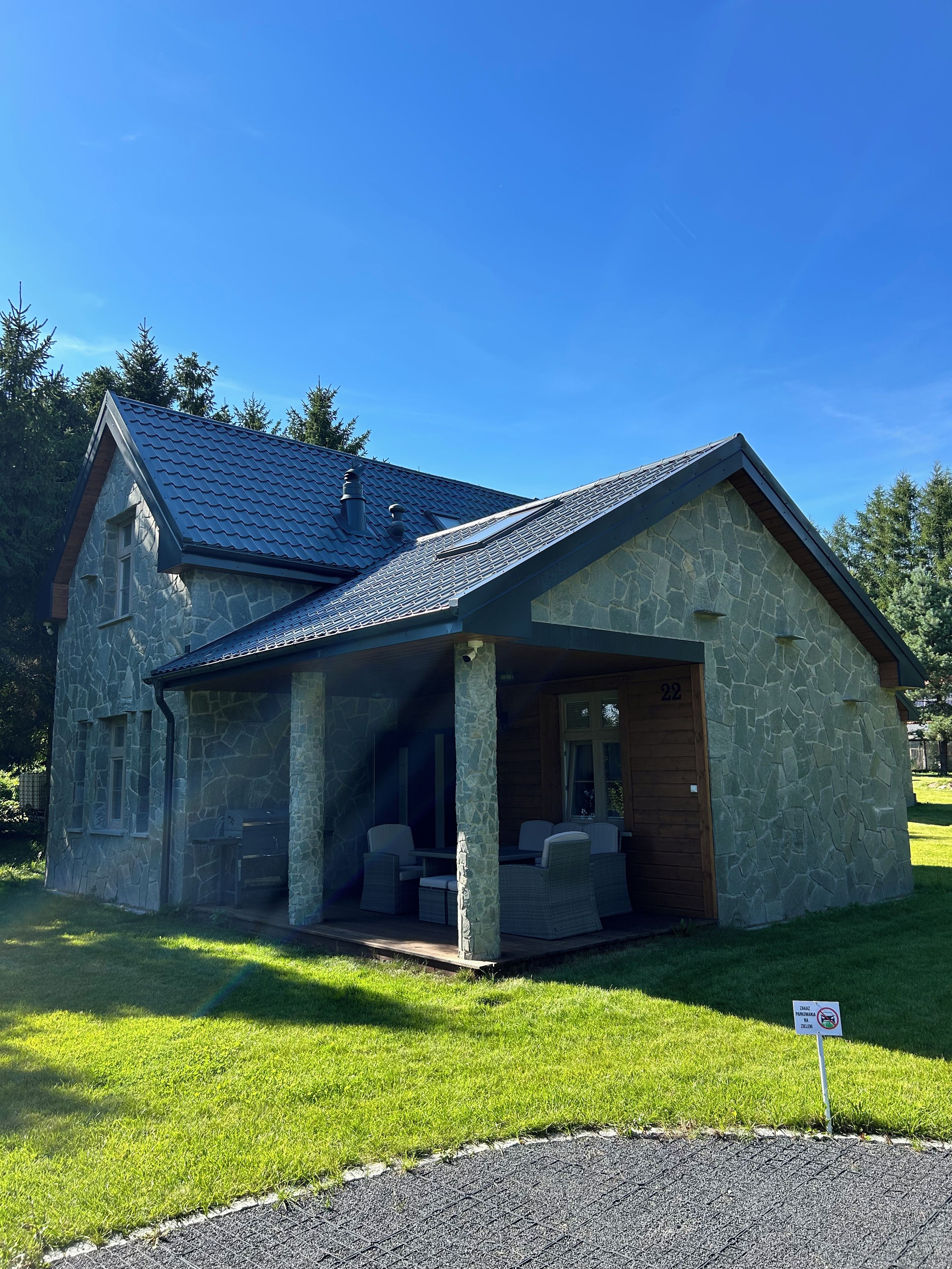 A stone house with a covered porch, a number 22 sign, and a no parking sign.
