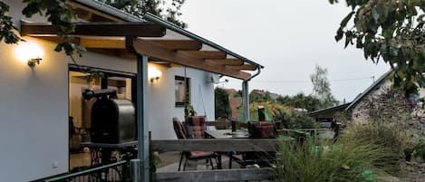 A house with a covered patio, outdoor seating, and a barbecue grill.