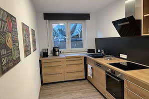Eine kompakte Küche mit Holzausstattung, einem eingebauten Ofen, einer schwarzen Arbeitsplatte und einem Fenster mit Bergblick.