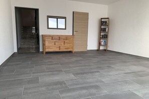 Una habitación con suelo de baldosas grises, un mueble de madera, una puerta cerrada y una estantería.