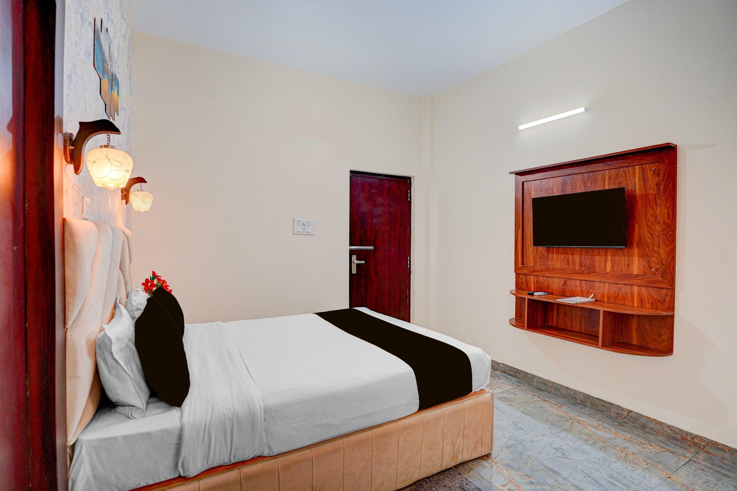 Quarto com cama, televisão na parede e porta.