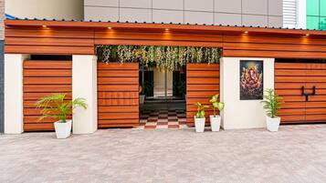 A building facade with a wooden panel design, a checkered floor pattern, and potted plants.