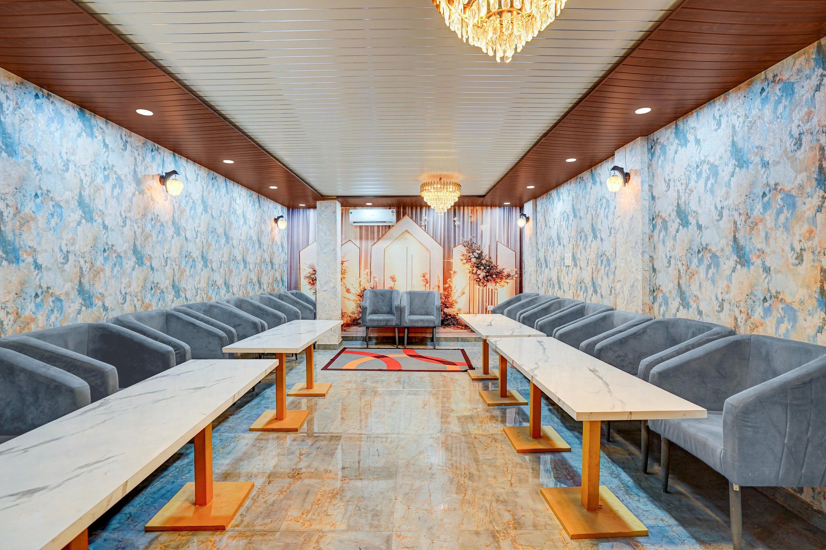 A conference room with marble flooring, grey upholstered chairs, and a chandelier.