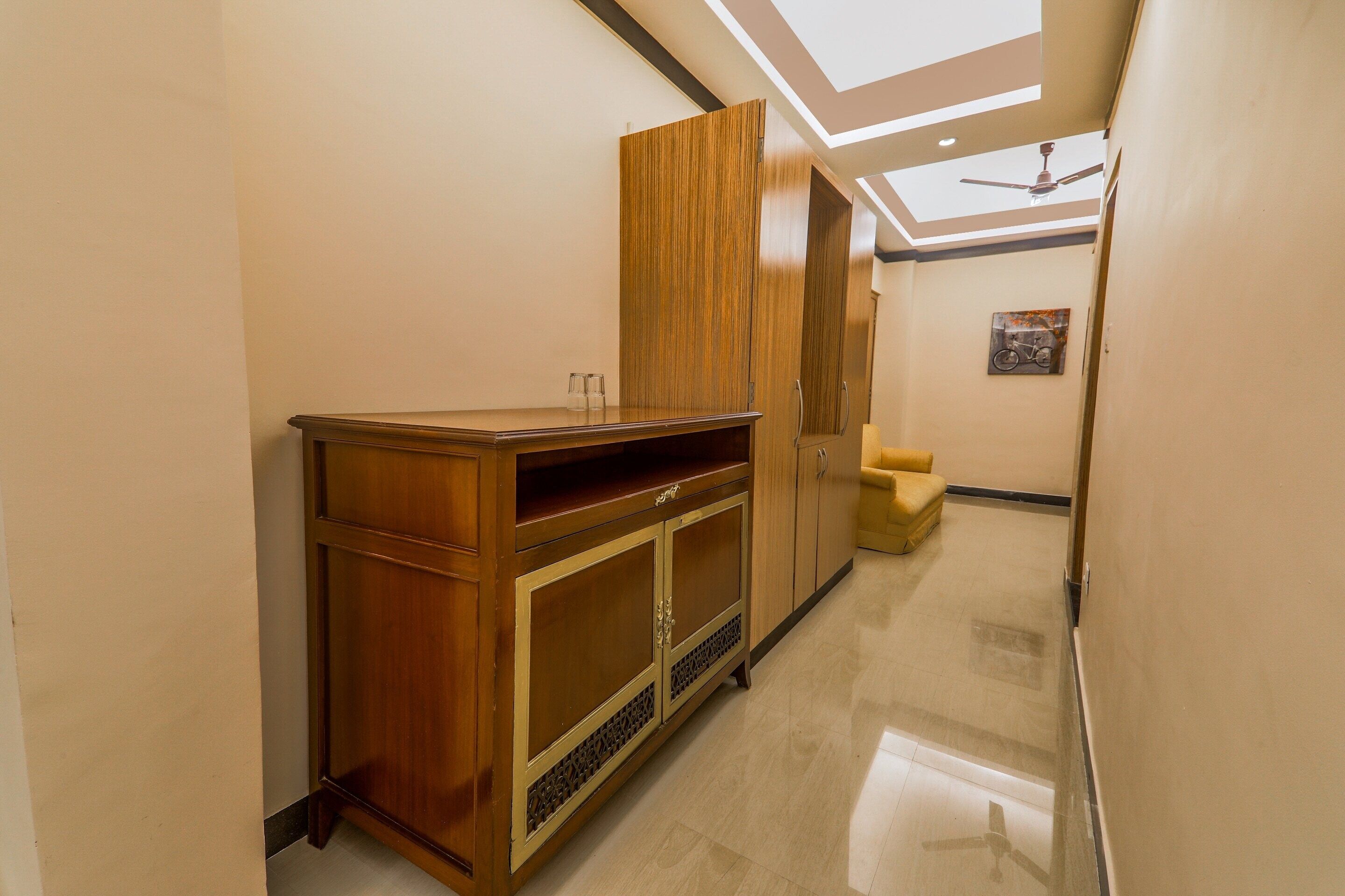 A hallway with a wooden cabinet, a ceiling fan, and a bicycle artwork on the wall.